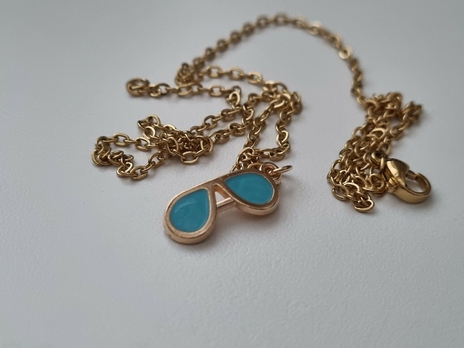 Guldfärgat halsband med ett par blå glasögon