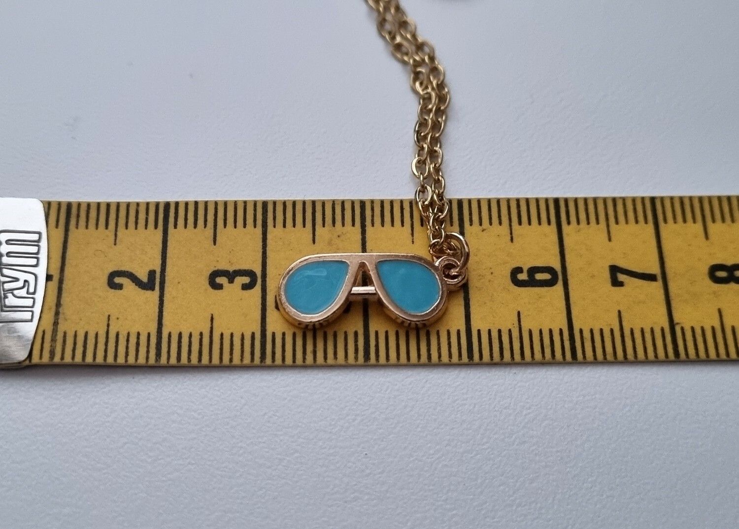 Guldfärgat halsband med ett par blå glasögon