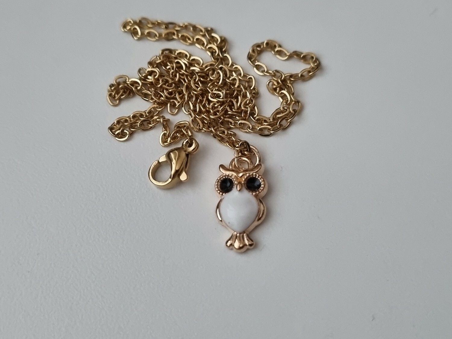 Guldfärgat halsband med en vit uggla