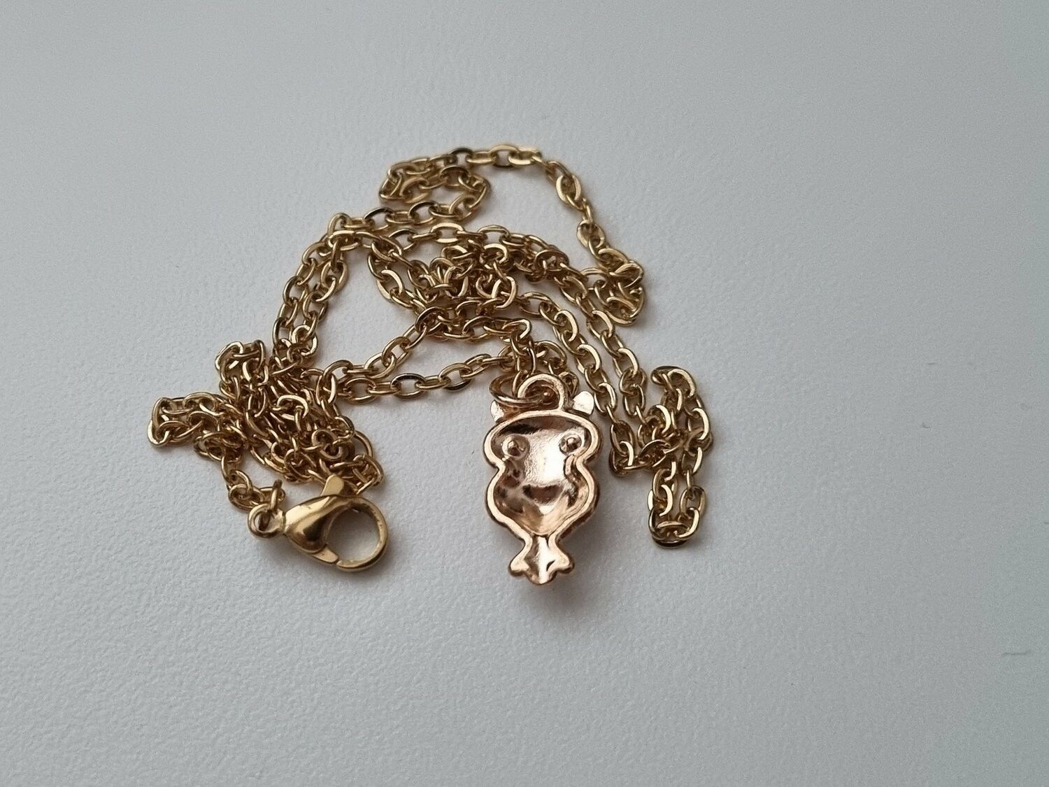 Guldfärgat halsband med en vit uggla