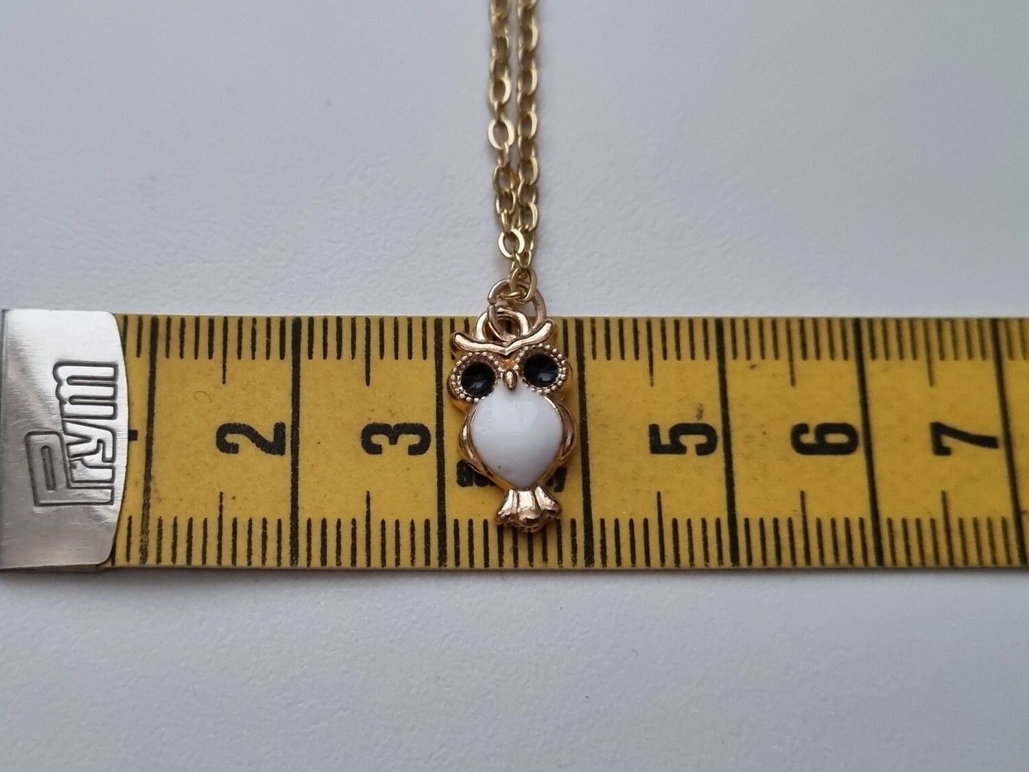 Guldfärgat halsband med en vit uggla