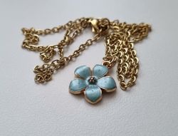 Guldfärgat halsband med en turkos blomma