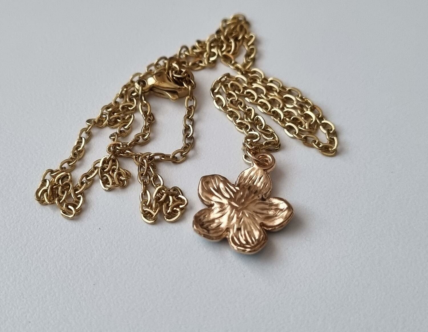 Guldfärgat halsband med en turkos blomma