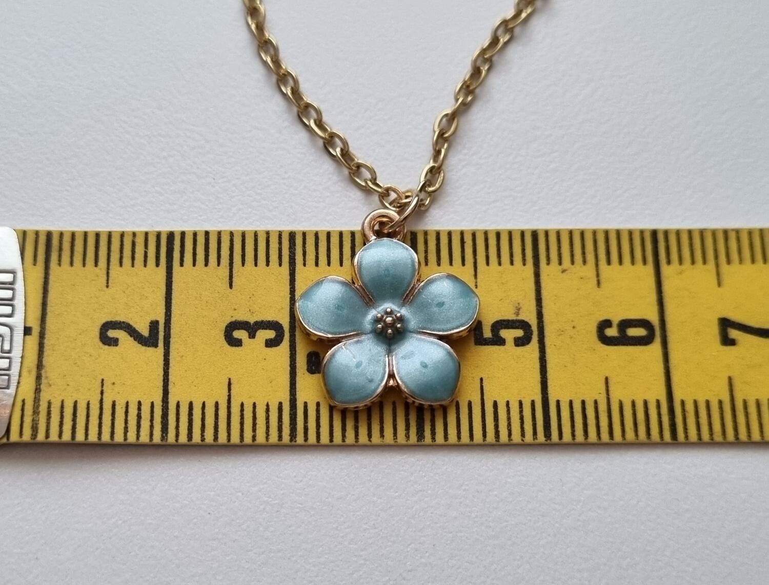 Guldfärgat halsband med en turkos blomma