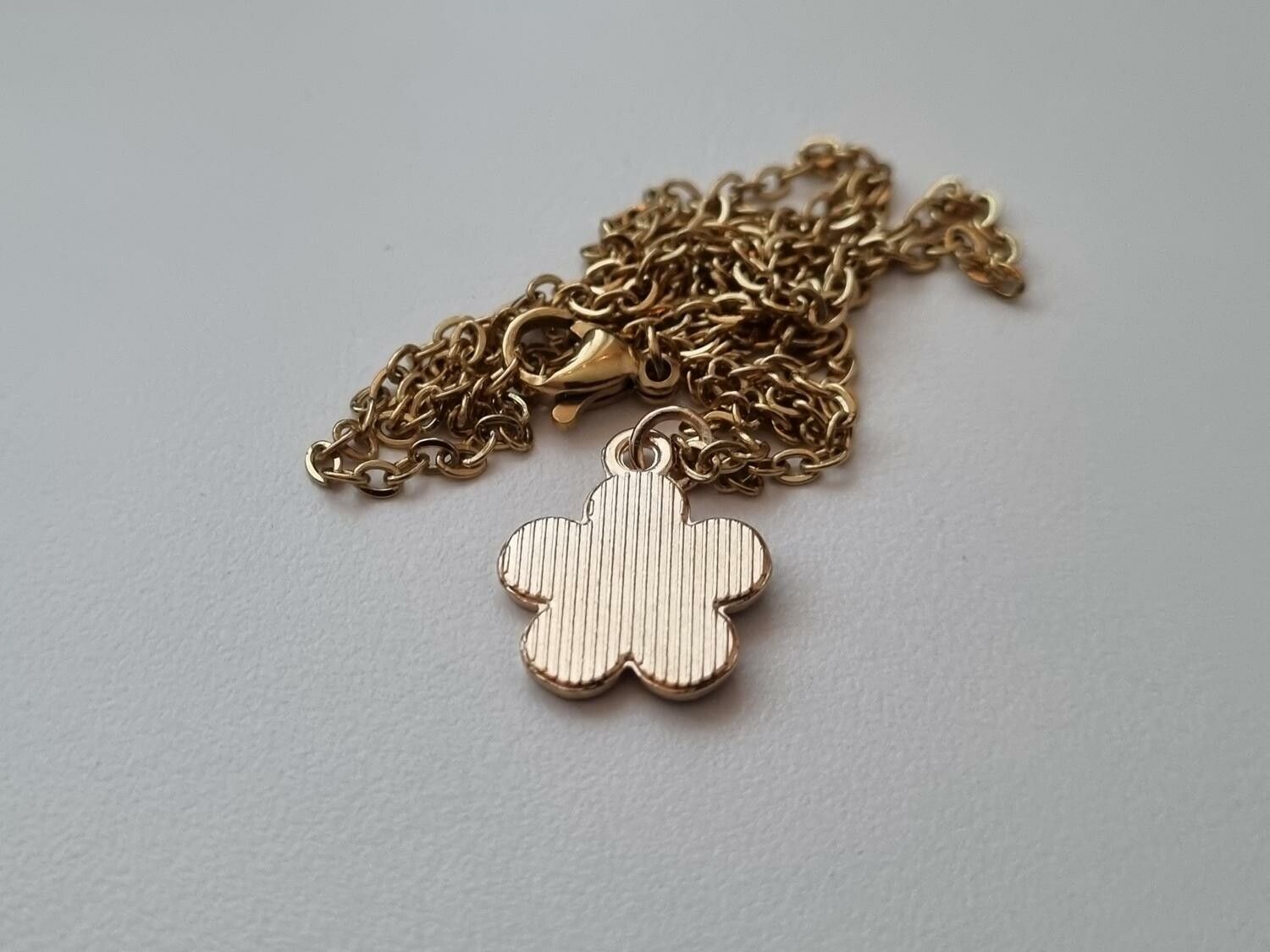 Guldfärgat halsband med en svart blomma / blomberlock