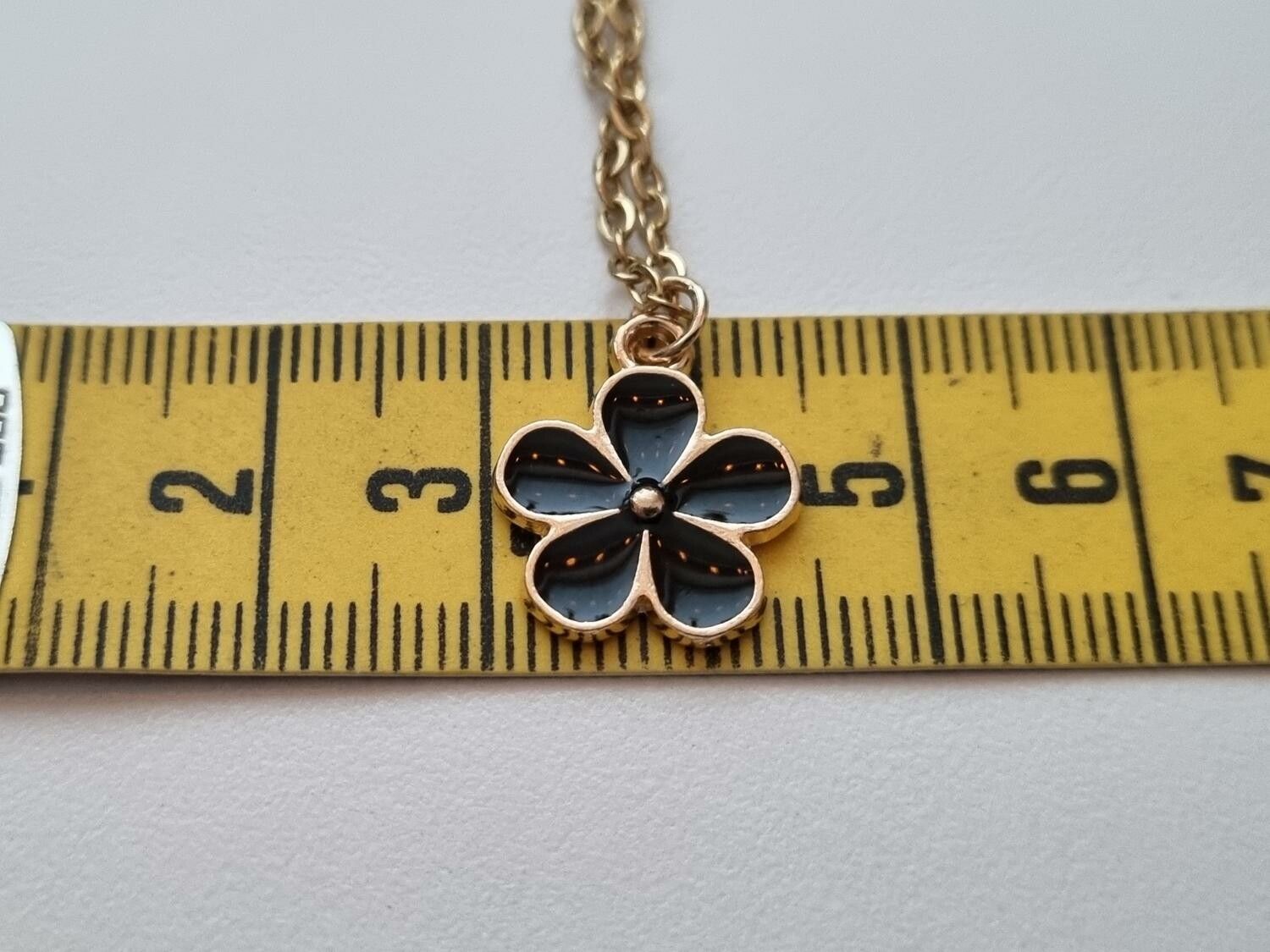 Guldfärgat halsband med en svart blomma / blomberlock