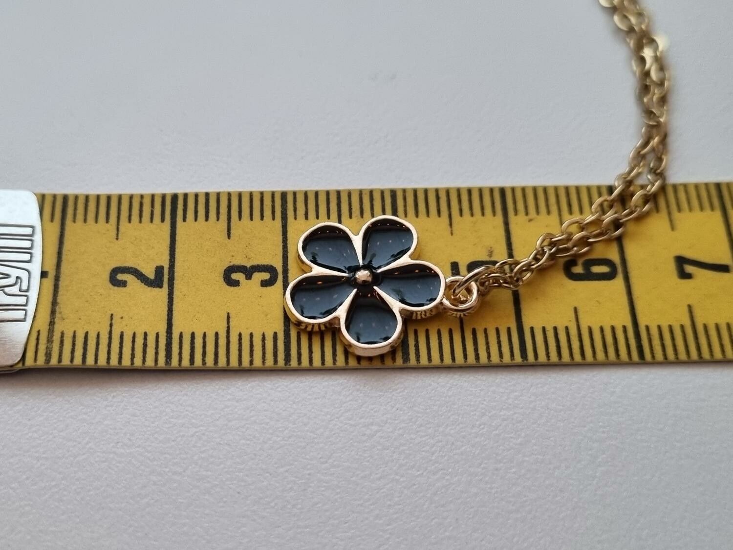 Guldfärgat halsband med en svart blomma / blomberlock