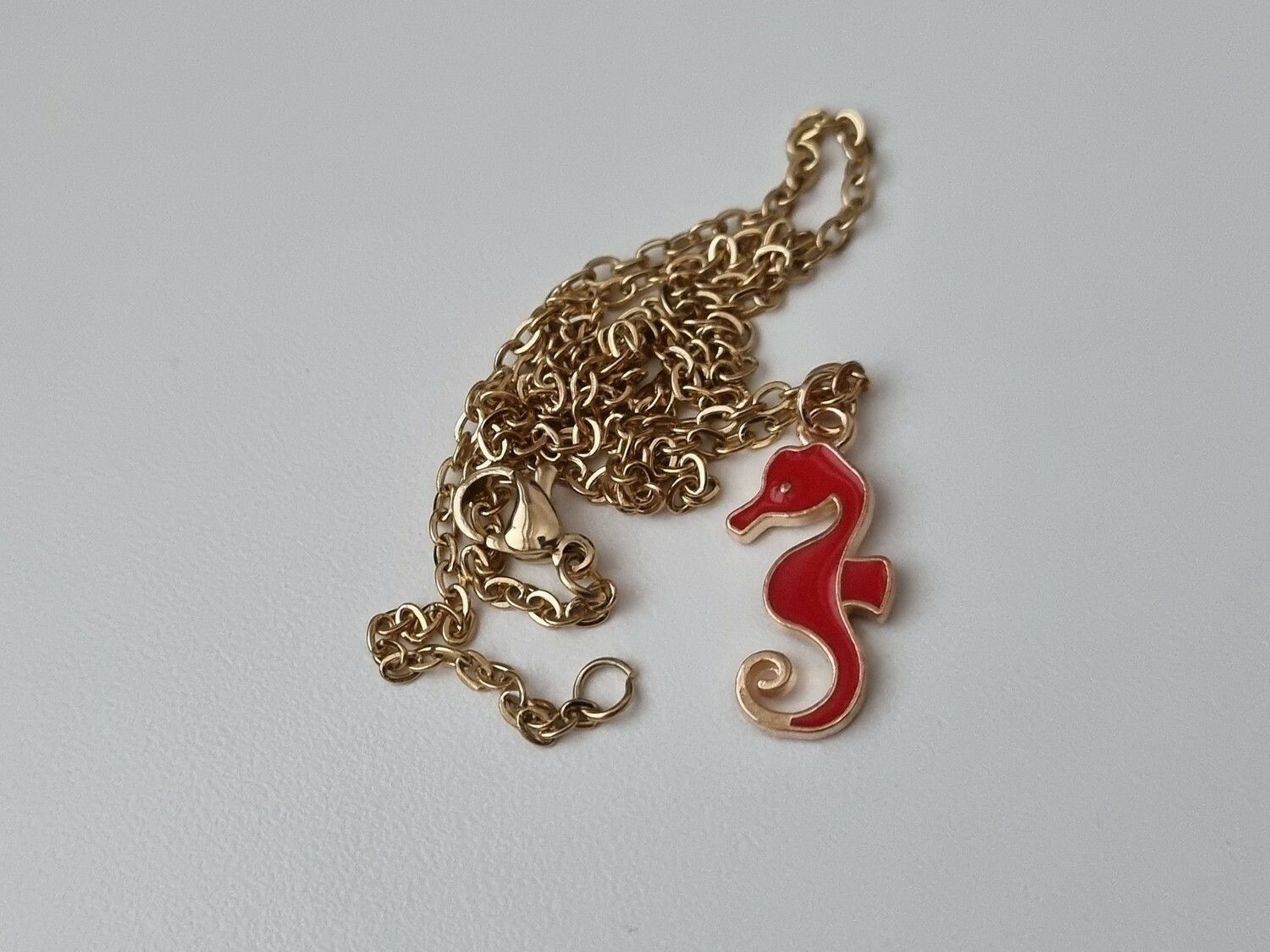 Guldfärgat halsband med en röd sjöhäst