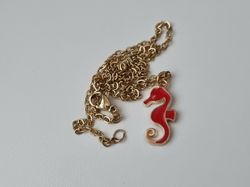 Guldfärgat halsband med en röd sjöhäst