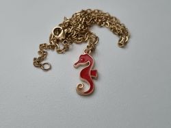 Guldfärgat halsband med en röd sjöhäst