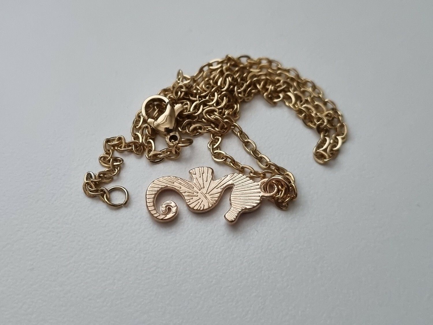 Guldfärgat halsband med en röd sjöhäst