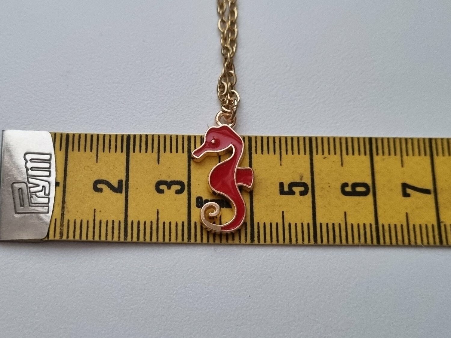 Guldfärgat halsband med en röd sjöhäst