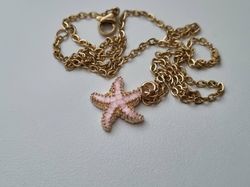 Guldfärgat halsband med en rosa sjöstjärna