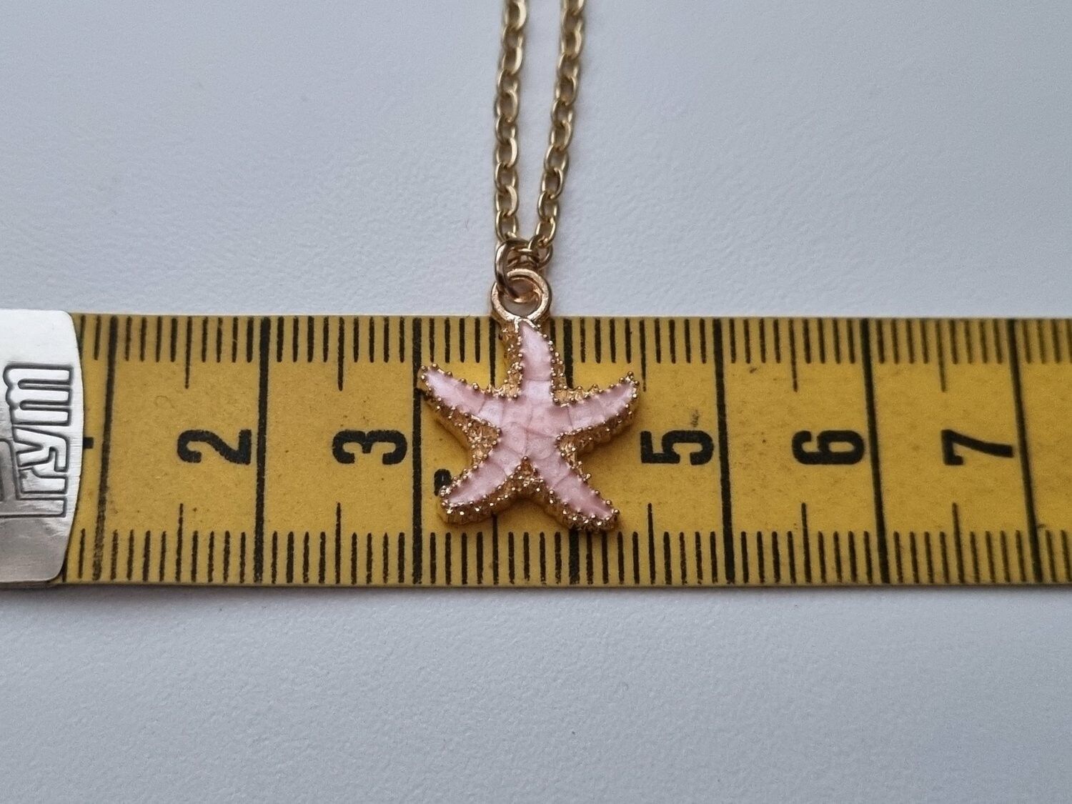 Guldfärgat halsband med en rosa sjöstjärna