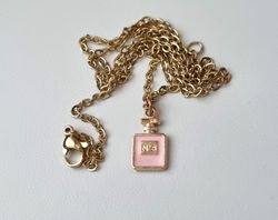 Guldfärgat halsband med en rosa parfymflaska