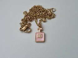 Guldfärgat halsband med en rosa parfymflaska