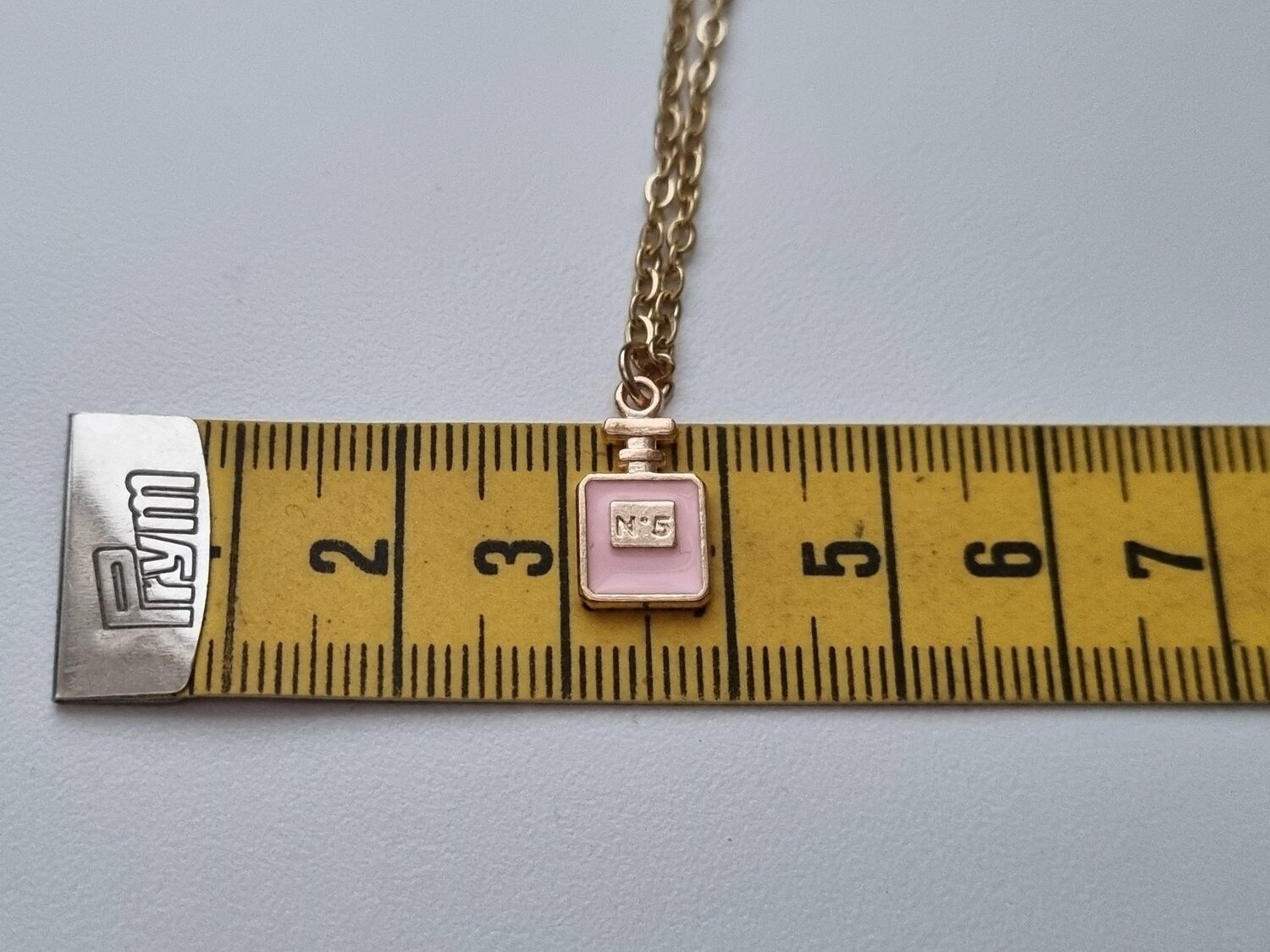 Guldfärgat halsband med en rosa parfymflaska