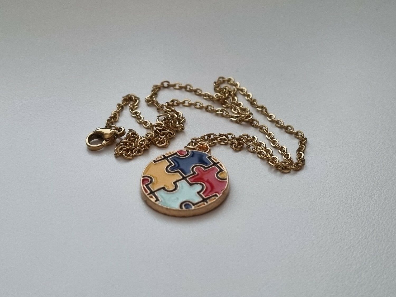 Guldfärgat halsband med en pusselbit / medvetenhet