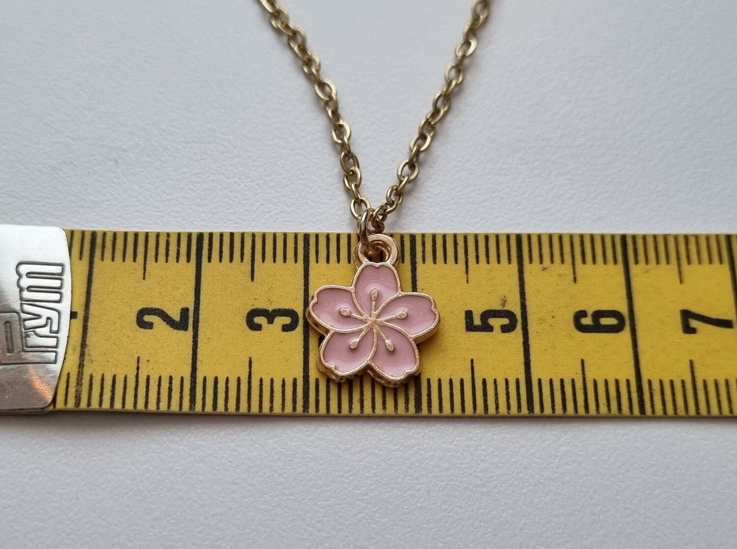 Guldfärgat halsband med en rosa blomma