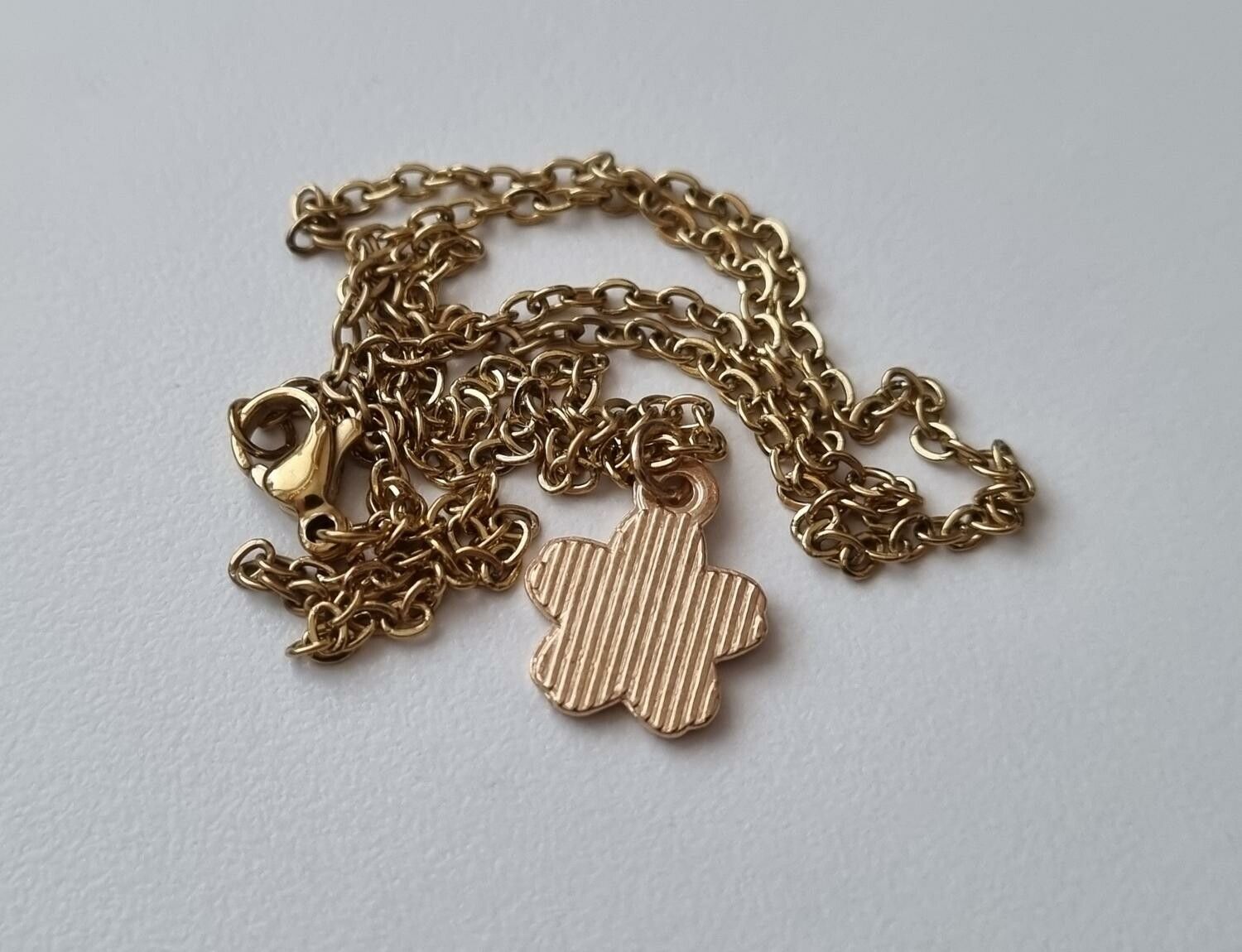 Guldfärgat halsband med en rosa blomma