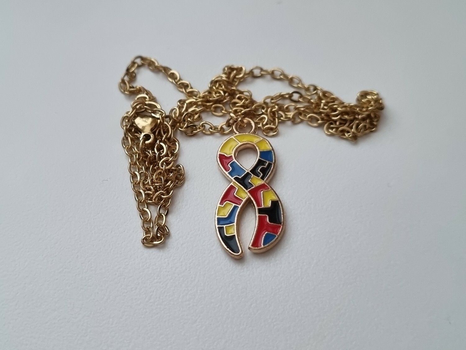 Guldfärgat halsband med en pusselbit / medvetenhet