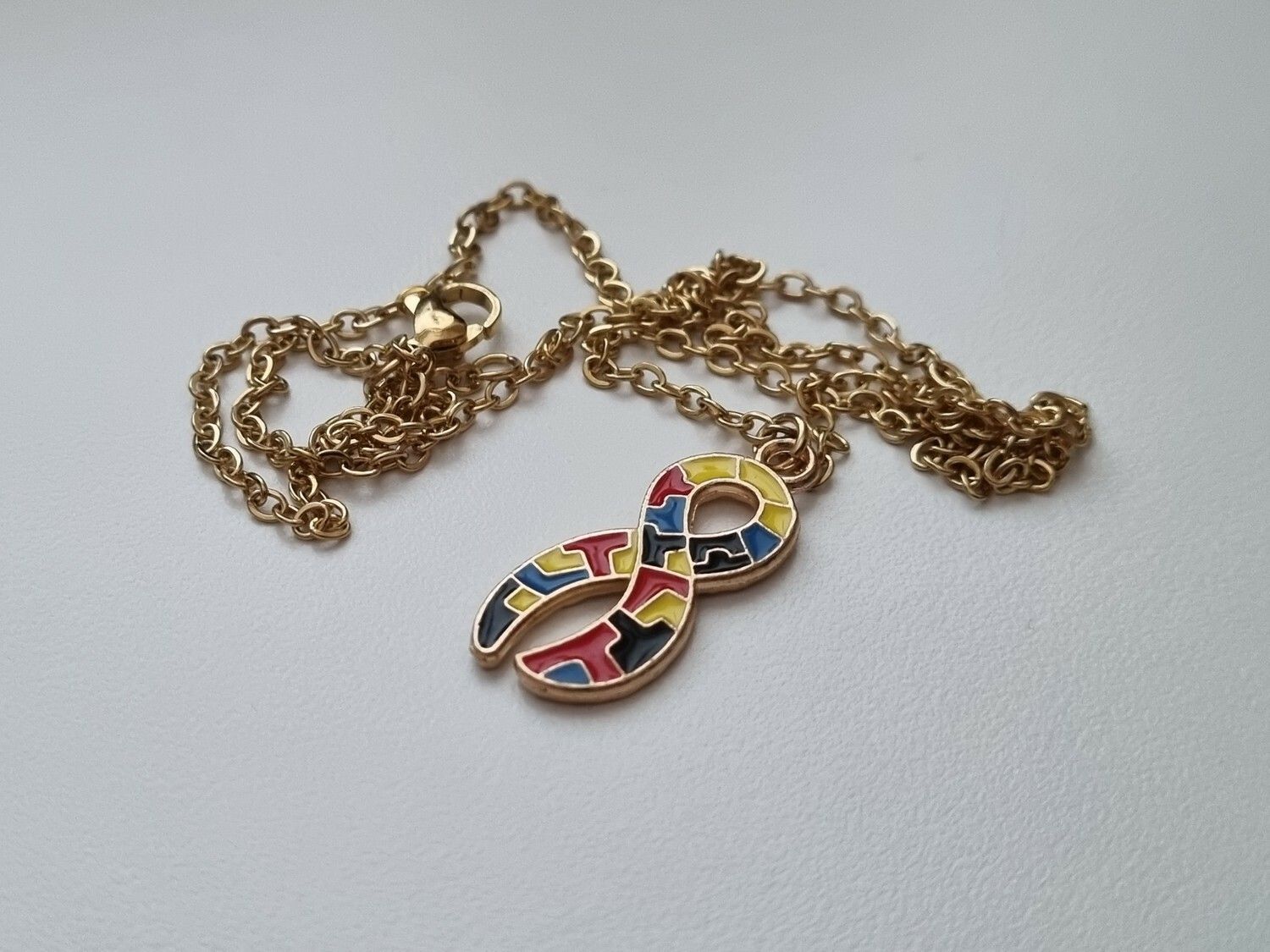 Guldfärgat halsband med en pusselbit / medvetenhet