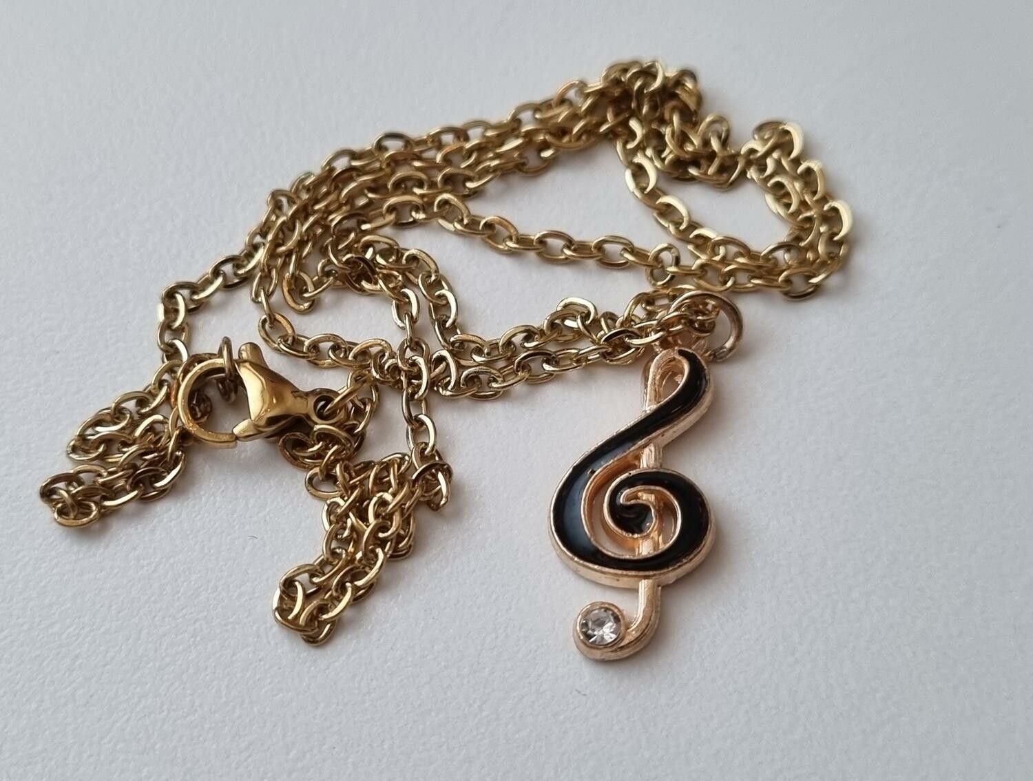 Guldfärgat halsband med en svart musiknot