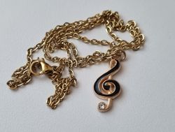 Guldfärgat halsband med en svart musiknot