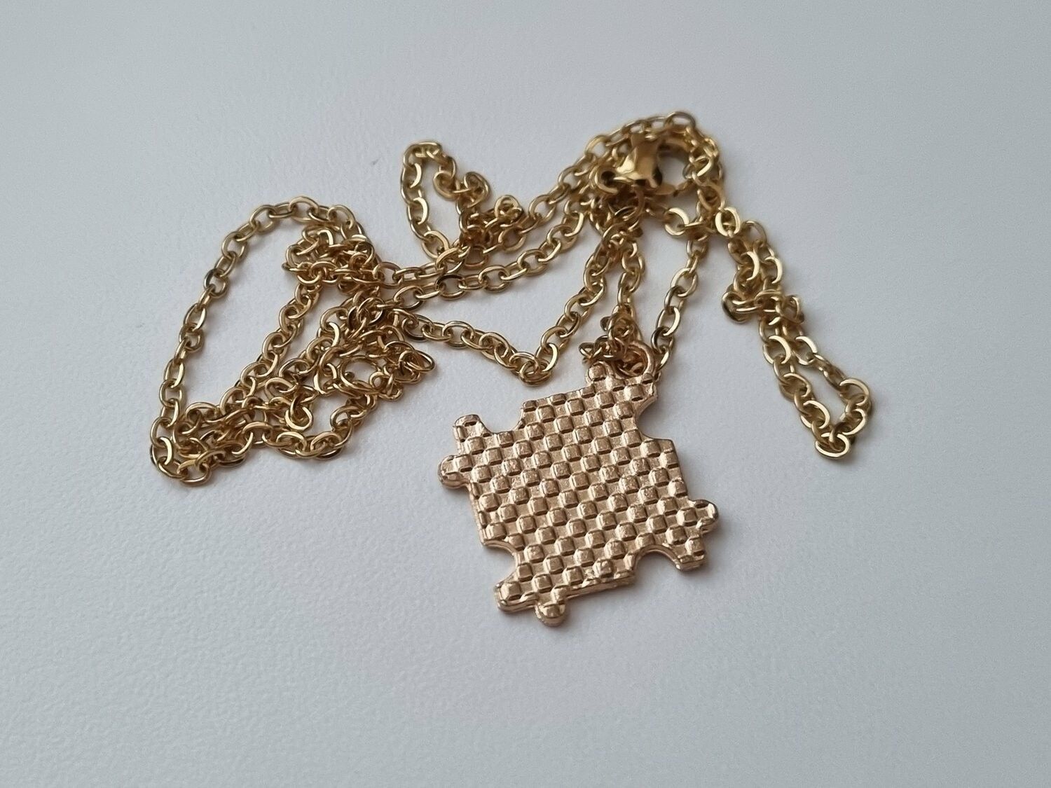 Guldfärgat halsband med en pusselbit / medvetenhet