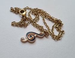 Guldfärgat halsband med en svart musiknot