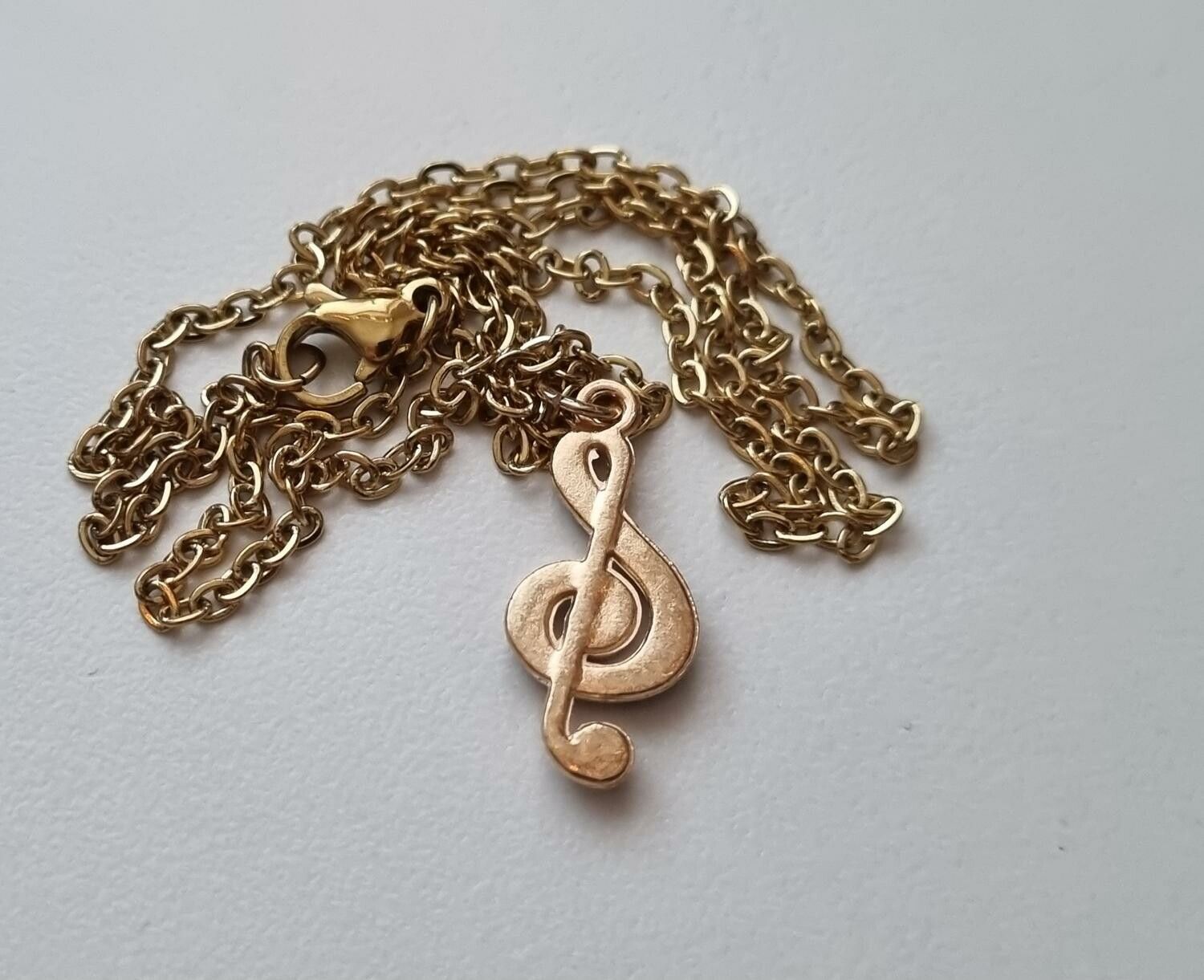 Guldfärgat halsband med en svart musiknot