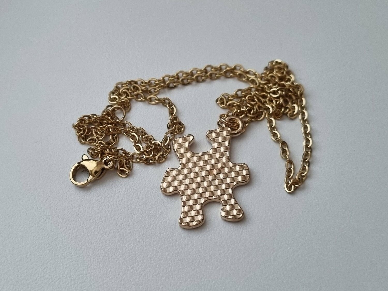 Guldfärgat halsband med en pusselbit / medvetenhet