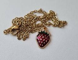 Guldfärgat halsband med en jordgubbe