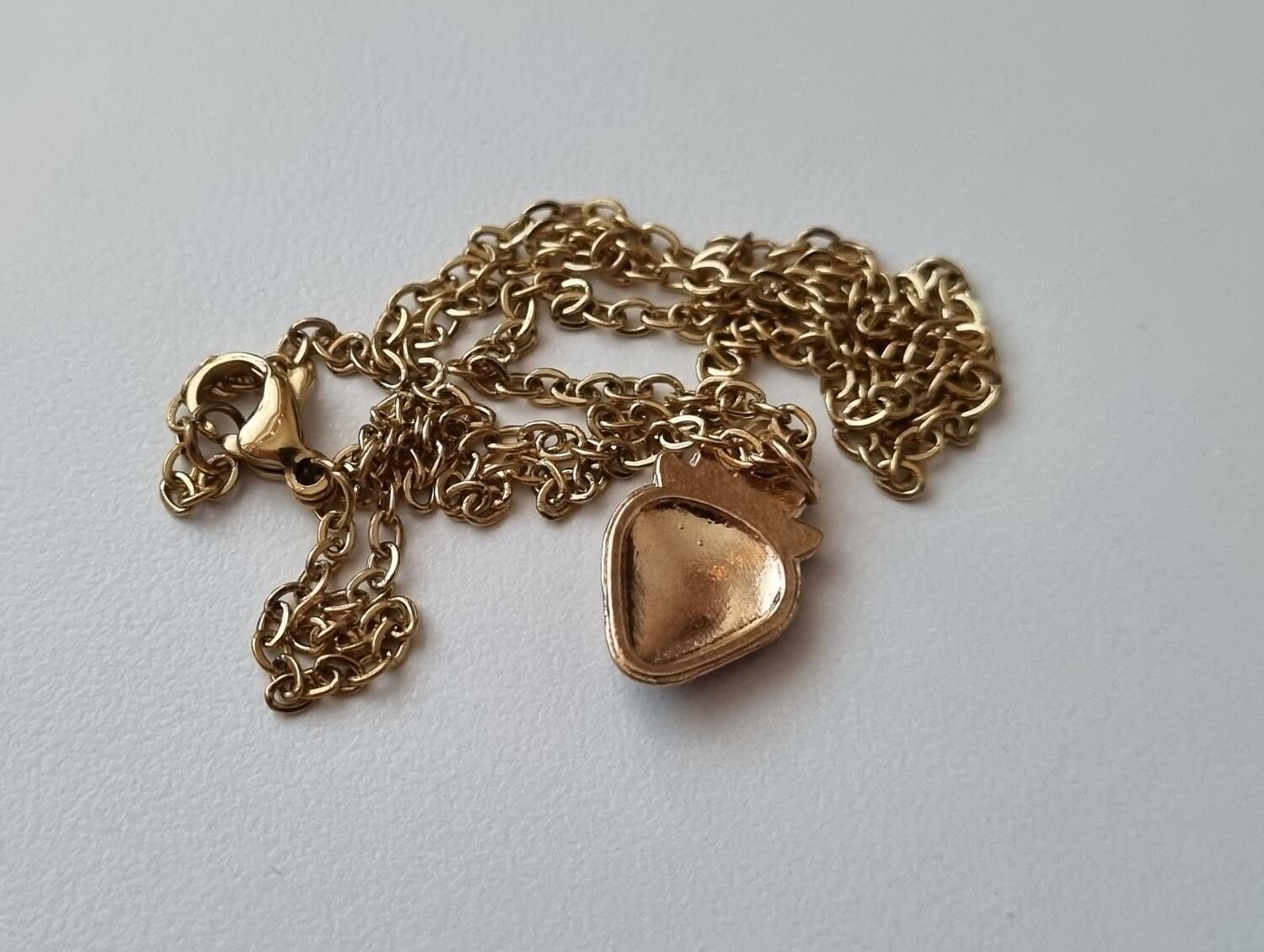 Guldfärgat halsband med en jordgubbe