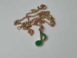 Guldfärgat halsband med en grön musiknot