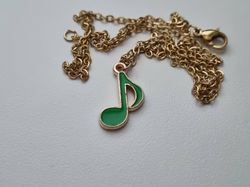 Guldfärgat halsband med en grön musiknot