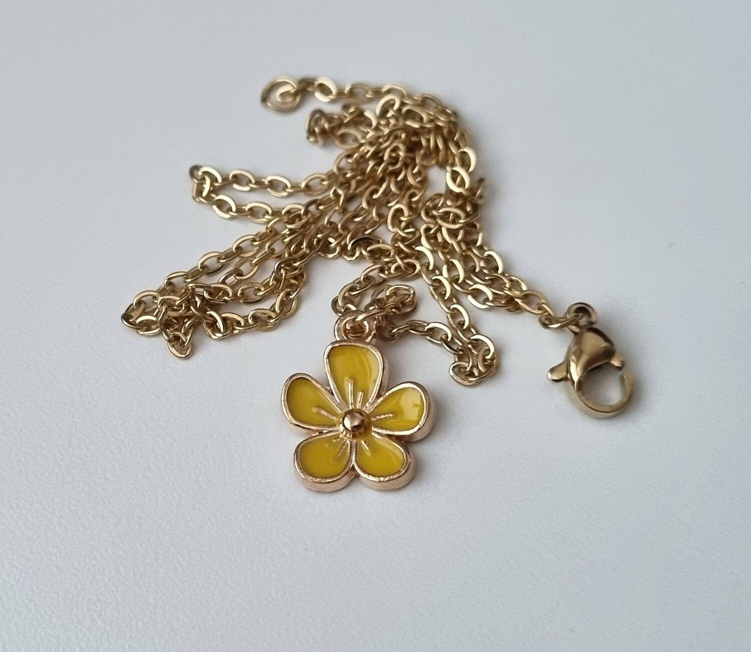 Guldfärgat halsband med en gul blomma
