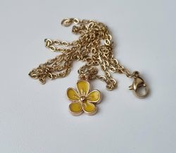 Guldfärgat halsband med en gul blomma