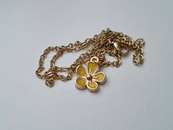 Guldfärgat halsband med en gul blomma