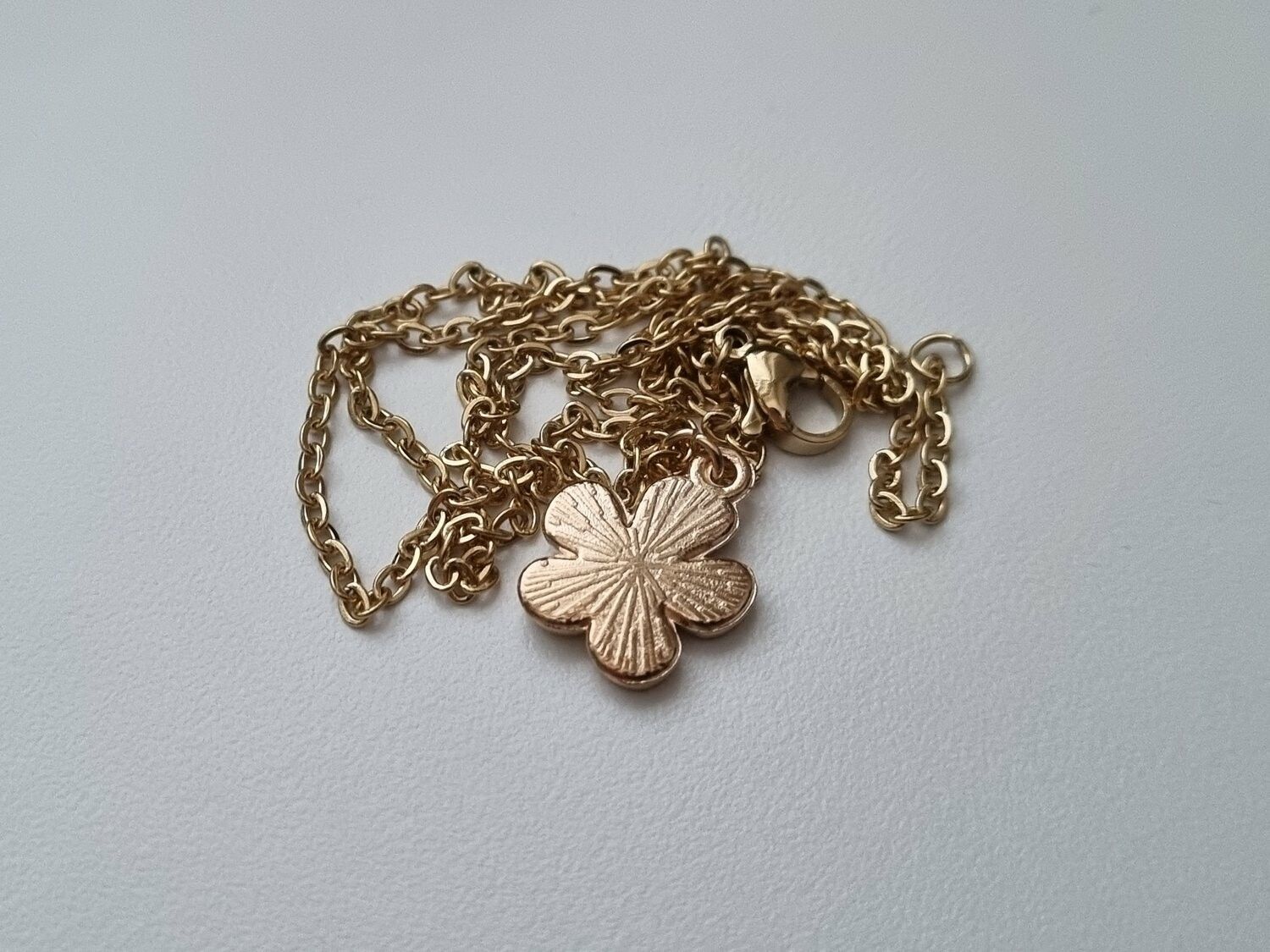 Guldfärgat halsband med en gul blomma