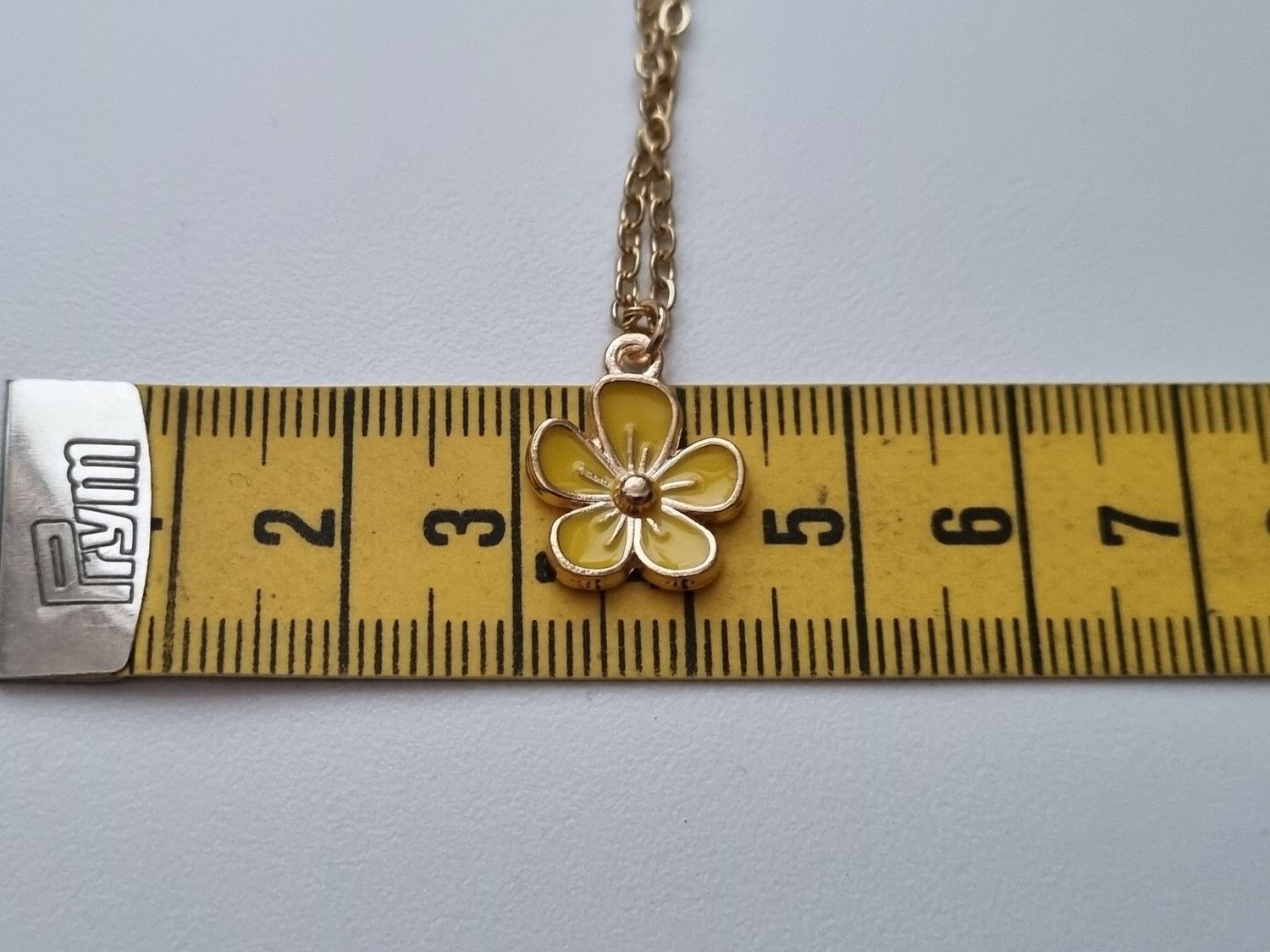 Guldfärgat halsband med en gul blomma