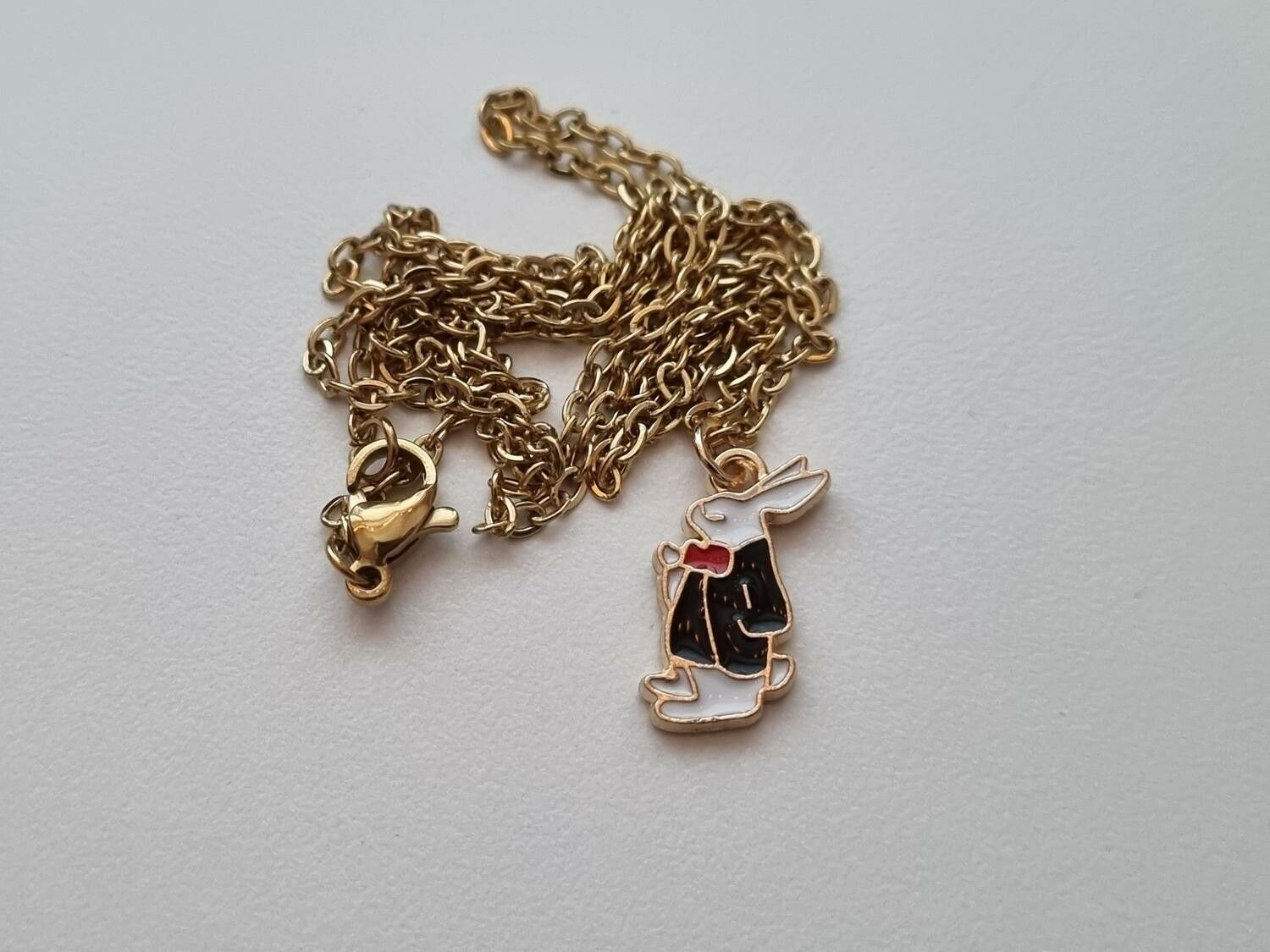 Guldfärgat halsband med en finklädd kanin i kostym