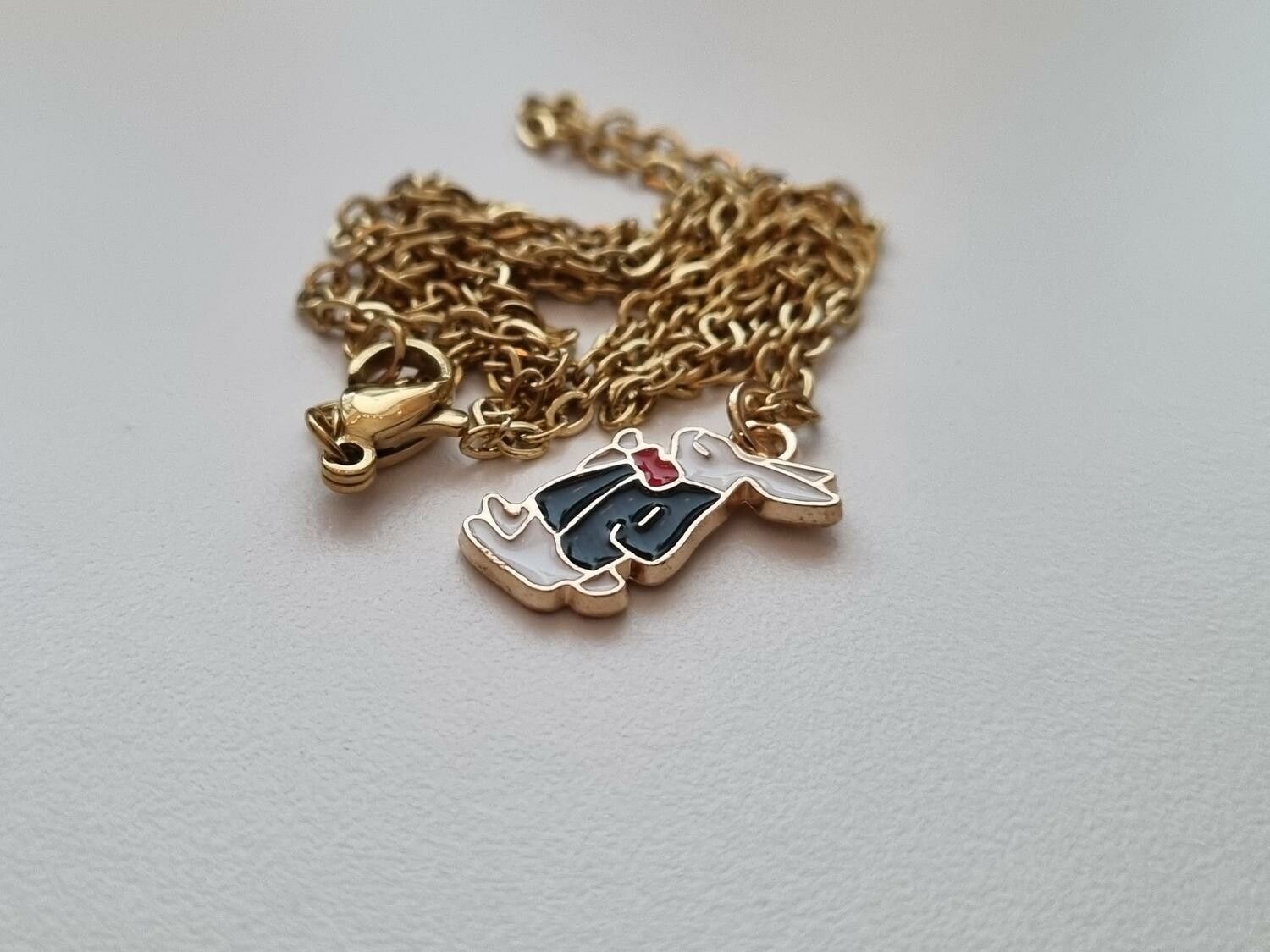 Guldfärgat halsband med en finklädd kanin i kostym