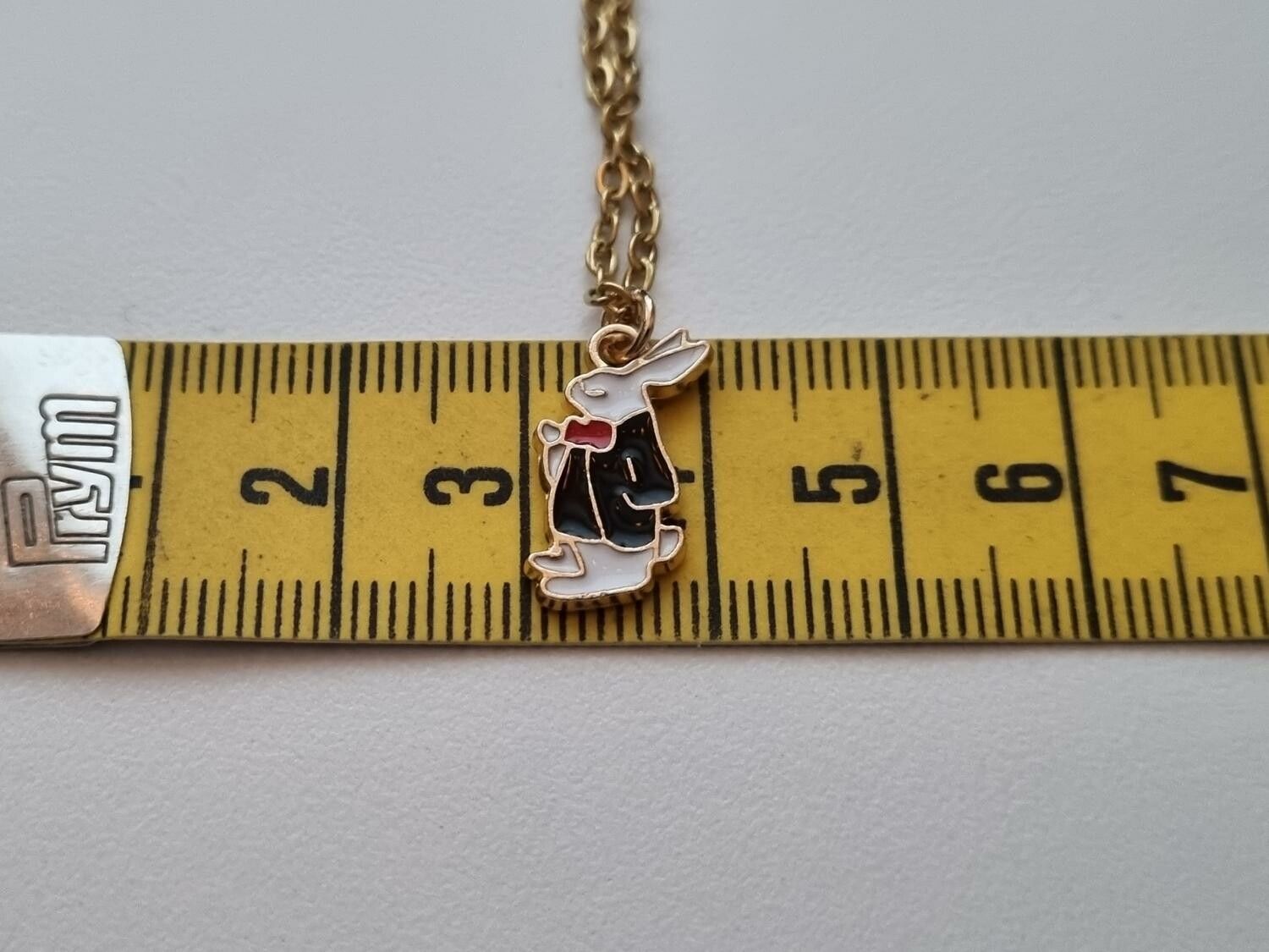 Guldfärgat halsband med en finklädd kanin i kostym