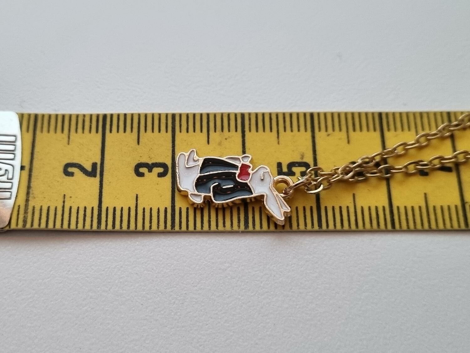 Guldfärgat halsband med en finklädd kanin i kostym