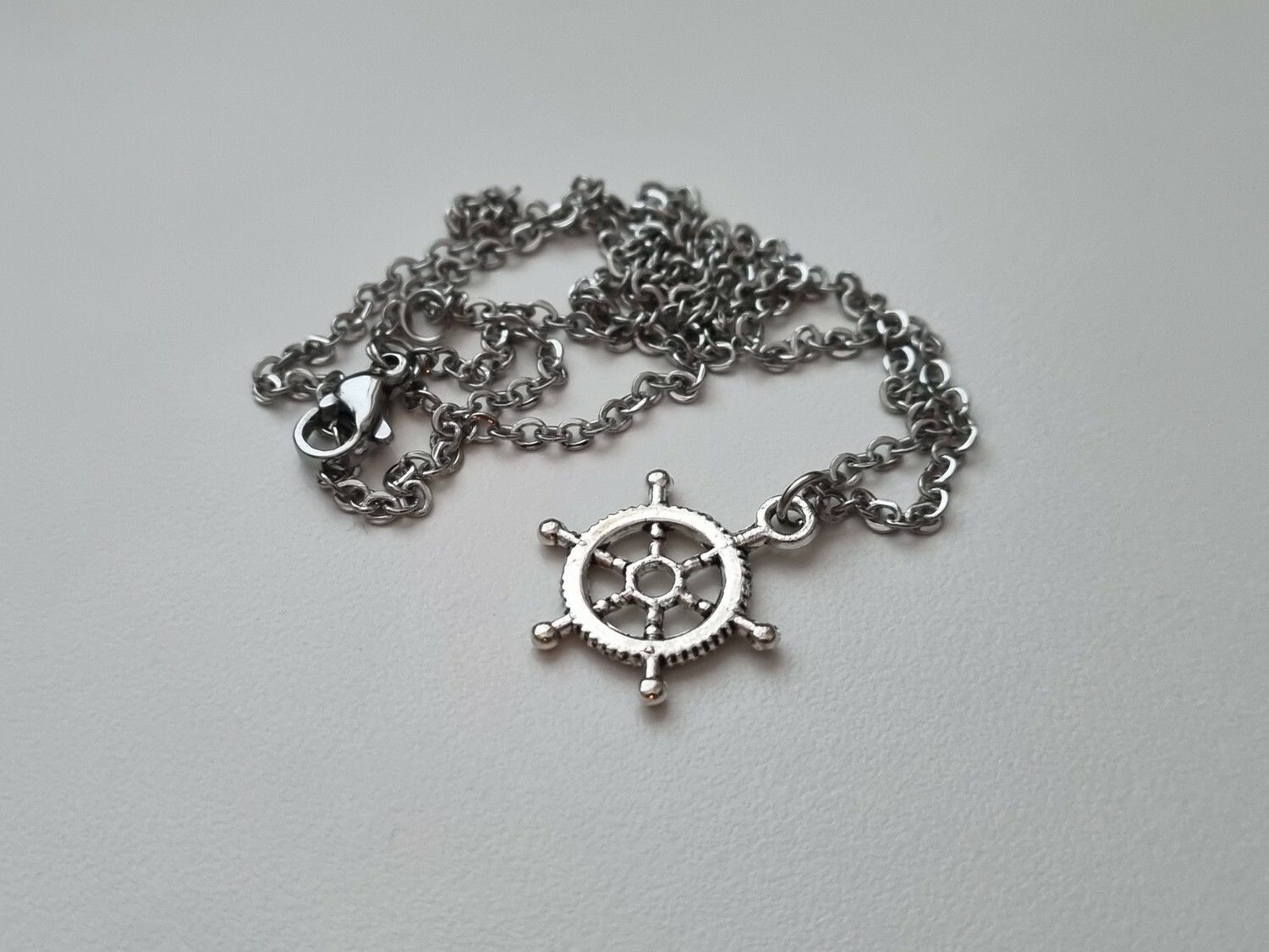 Silverfärgat halsband med en fartygsratt