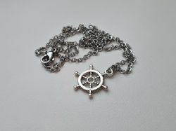 Silverfärgat halsband med en fartygsratt