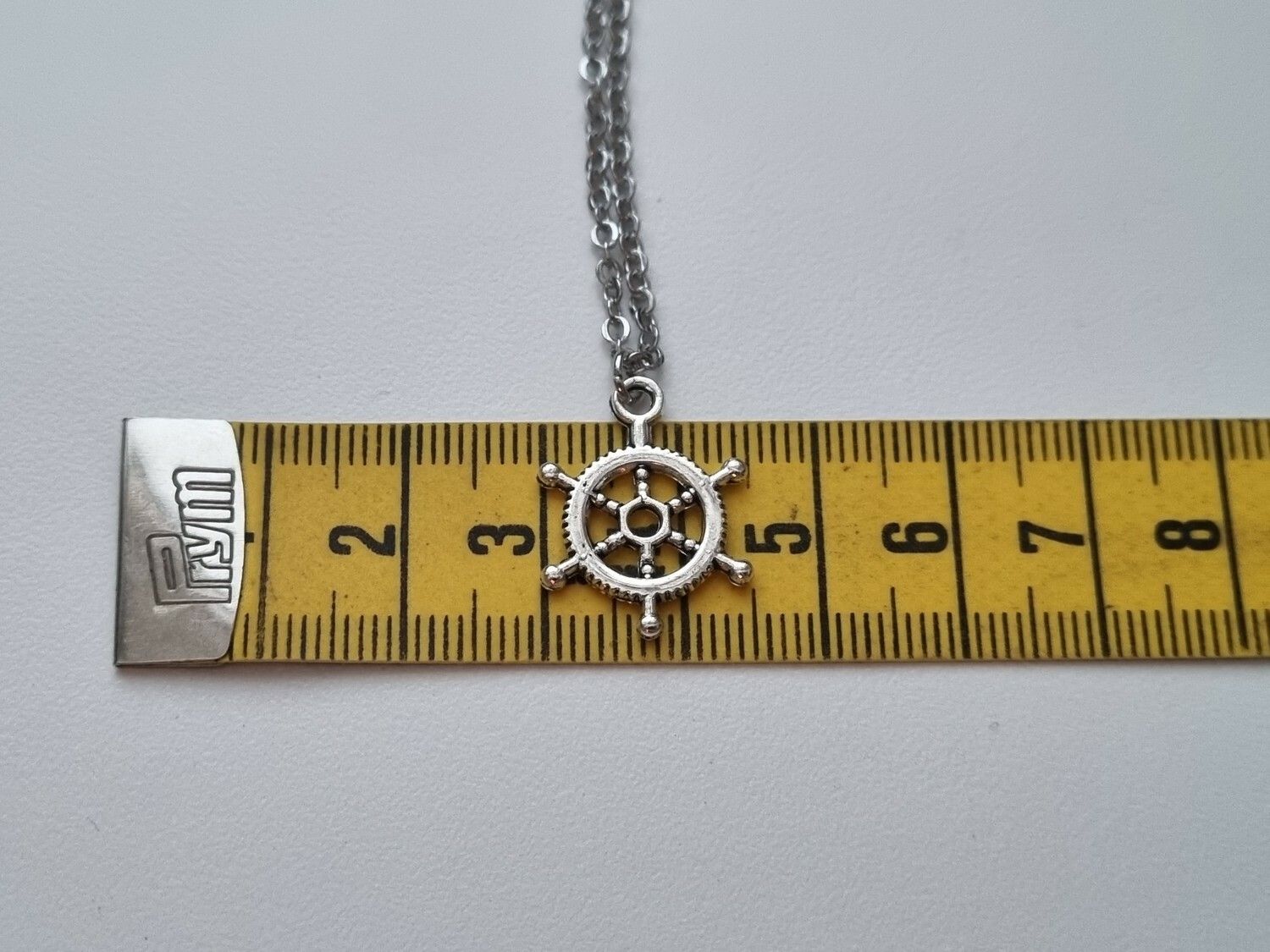 Silverfärgat halsband med en fartygsratt