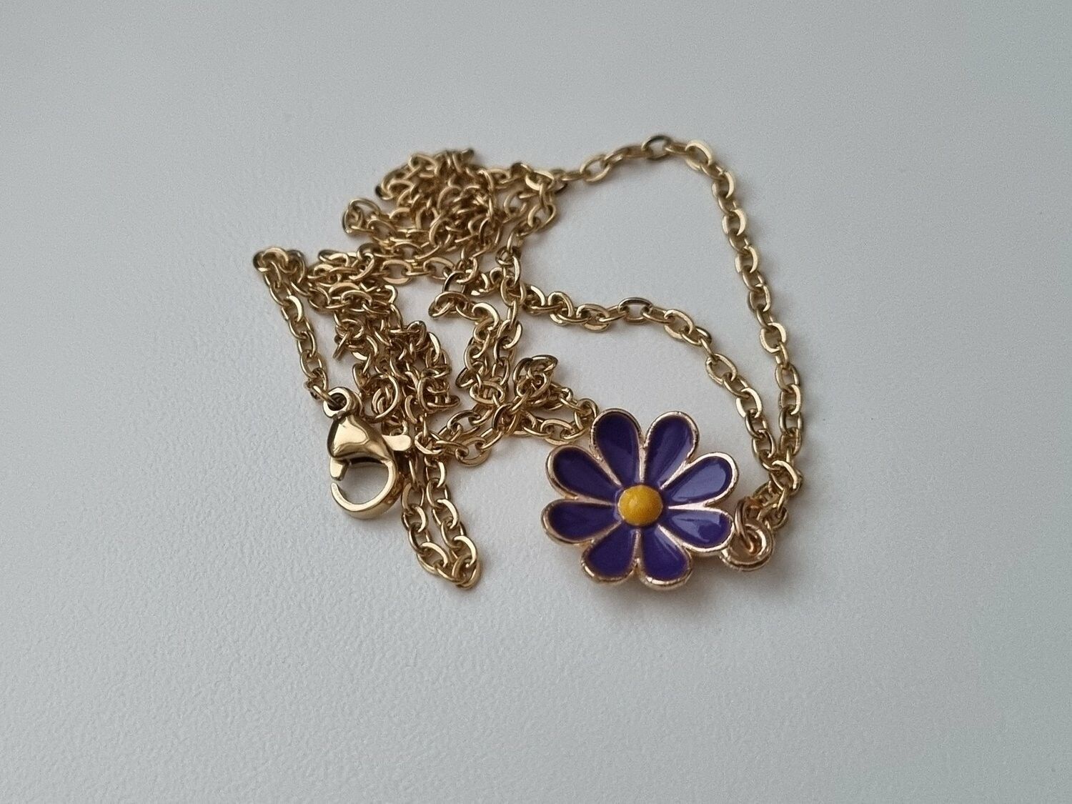 Guldfärgat halsband med en blomma