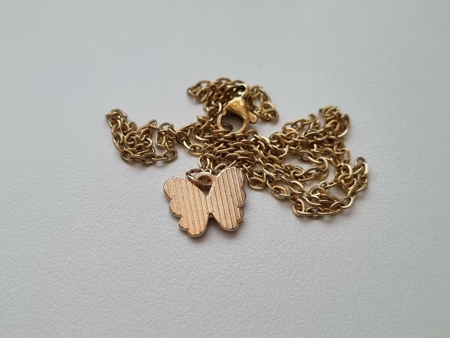 Guldfärgat halsband med en blå fjäril / fjärilsberlock